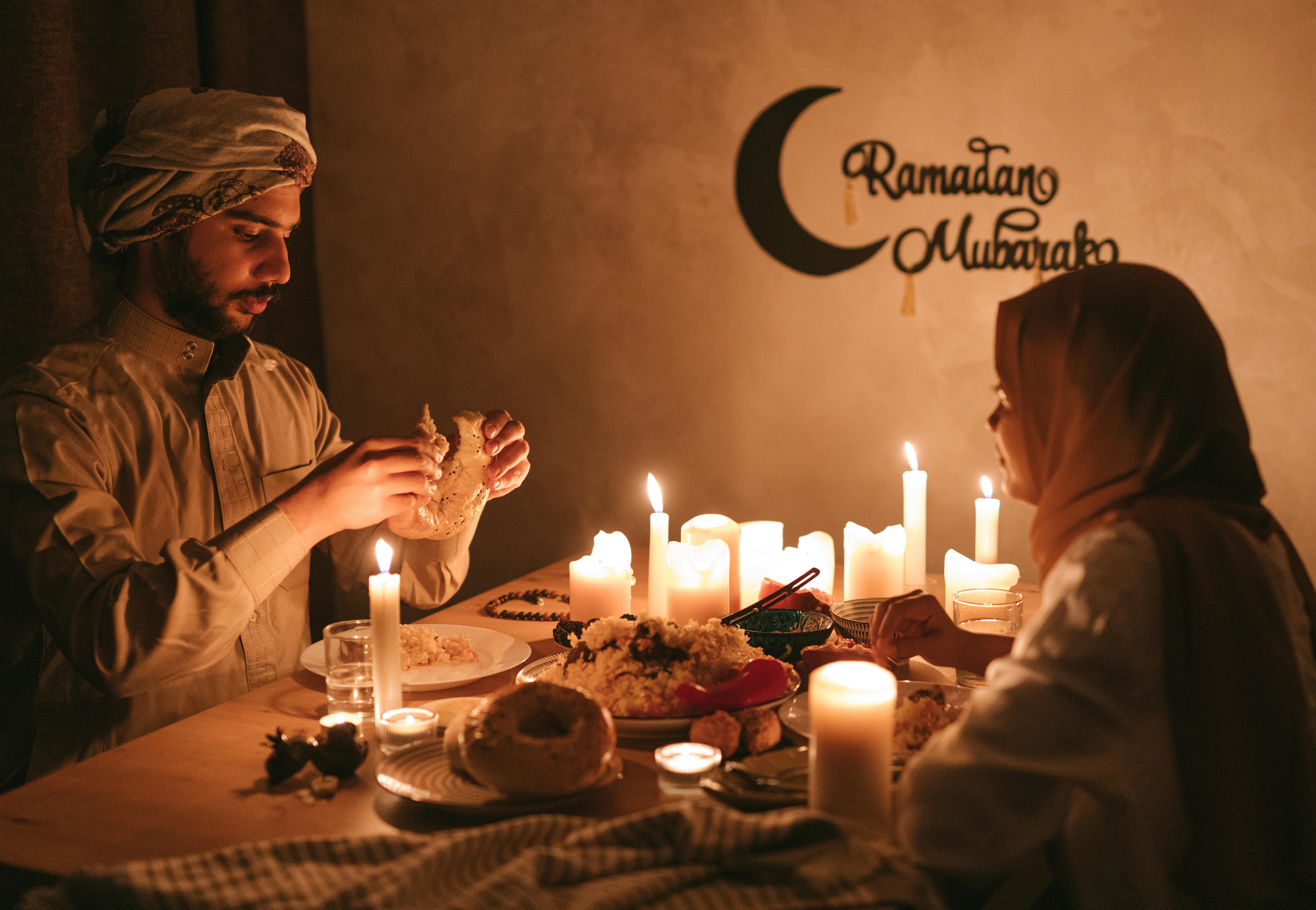 photo of couple eating food at night by several lit candles at Ramadan